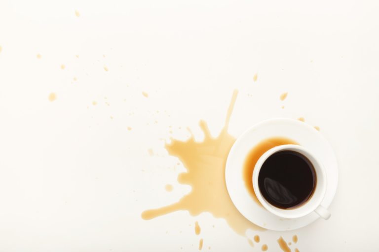 Coffee cup and spilt espresso on white background